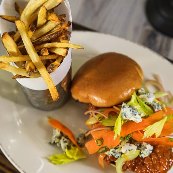 A West Main Taproom burger with blue cheese, carrots, and celery, served with a side of fries.
