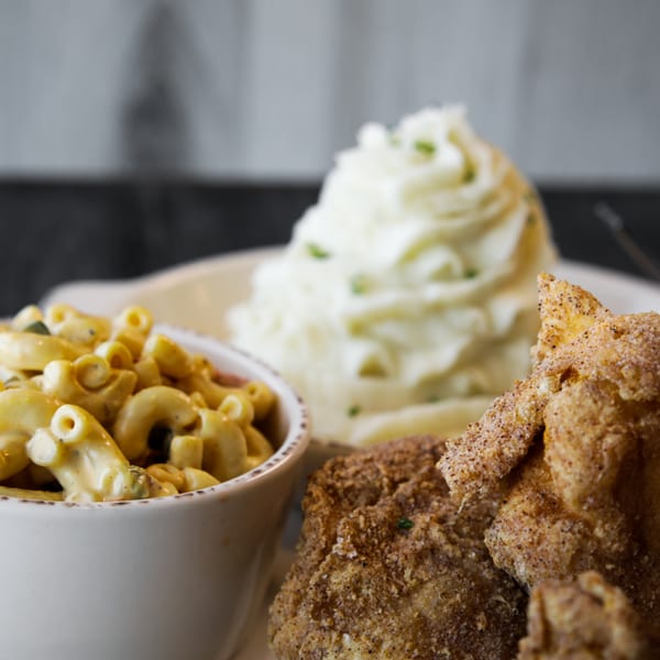 West Main Taproom's fried chicken, macaroni and cheese, and mashed potatoes on a white plate.